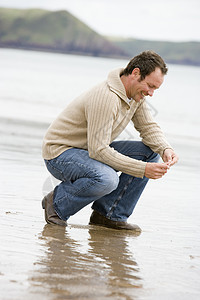 男人在海滩上跪在海边微笑视图思维海洋大海低角度季节偏移角海岸线男性支撑图片