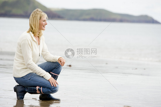 女人跪在海滩上微笑图片