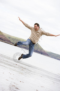 男人在海滩上欢笑的跳跃图片