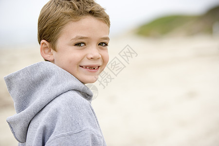 站在沙滩上微笑的年轻男孩图片
