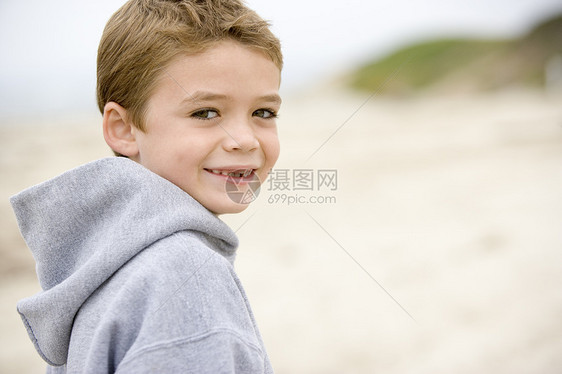 站在沙滩上微笑的年轻男孩图片