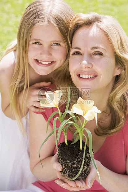 母亲和女儿在户外微笑着花朵的鲜花相机植物父母花园农村季节孩子女士园艺公园图片
