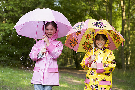 两个姐妹在雨雨中户外 带着雨伞微笑两个人孩子相机女孩雨鞋靴子庇护所姐姐塑料袋农村图片