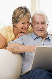 在客厅的情侣带着笔记本电脑微笑技术中年妻子上网女性男人成人互联网冲浪者两个人图片