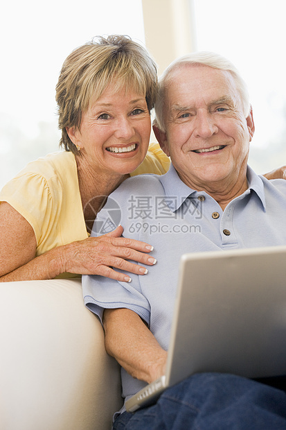 在客厅的情侣带着笔记本电脑微笑妻子技术冲浪者成人上网女士家庭女性男人男性图片
