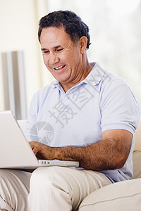 在客厅的男人 手持笔记本电脑微笑互联网男性技术上网沙发家庭成人婴儿女士长度图片