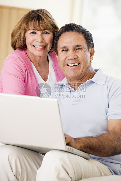 在客厅的情侣带着笔记本电脑微笑男性女性相机女士妻子银色家庭拉丁沙发中年图片
