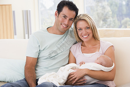 在客厅的一对夫妇 与婴儿微笑母亲中年女孩拥抱三个人家庭女士男性女儿妈妈图片