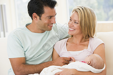 在客厅的一对夫妇 与婴儿微笑拥抱父亲爸爸男人中年女性夫妻女孩新生母亲图片