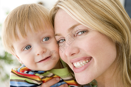 母亲在起居室抱着婴儿微笑水平女士女性拥抱儿童照顾家长儿子男性妈妈图片