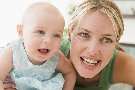 母亲在起居室 婴儿微笑相机家长照顾女性女士女孩妈妈拥抱两个人水平图片