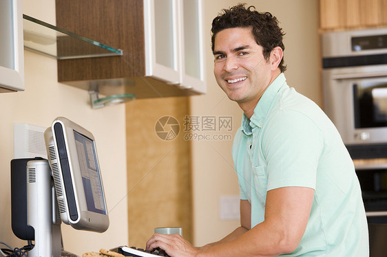 厨房里的男人使用电脑和微笑水平年轻人男性工作站互联网相机冲浪技术桌子成人图片