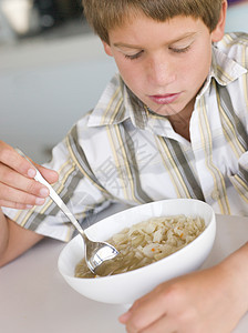 在厨房吃汤的男孩一个男孩食物食品饮食小男孩孩子儿童孩子们倒胃图片