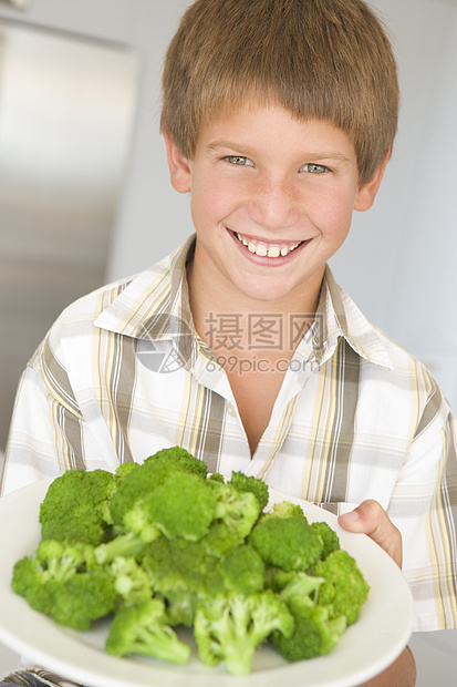 厨房里的小男孩在吃花椰菜 笑着小吃孩子们孩子健康饮食饮食零食一个男孩儿童绿色蔬菜图片