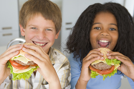 两个在厨房的小孩 笑着吃芝士汉堡食客饮食友谊孩子小男孩健康食物儿童朋友们食品图片