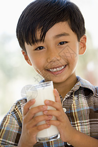 在室内喝着微笑的牛奶的年轻男孩奶制品食品小男孩玻璃食物孩子们儿童孩子一个男孩图片