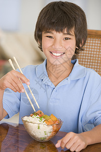 饭厅的年轻男孩在吃中国食物时微笑着笑外卖食品小男孩美食儿童筷子男生饮食用具中餐图片