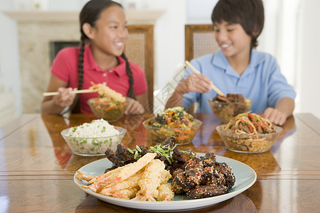 两个小孩在饭厅吃中国菜 笑着笑着家庭中餐青春期孩子们微笑孩子女孩美食姐姐食品图片