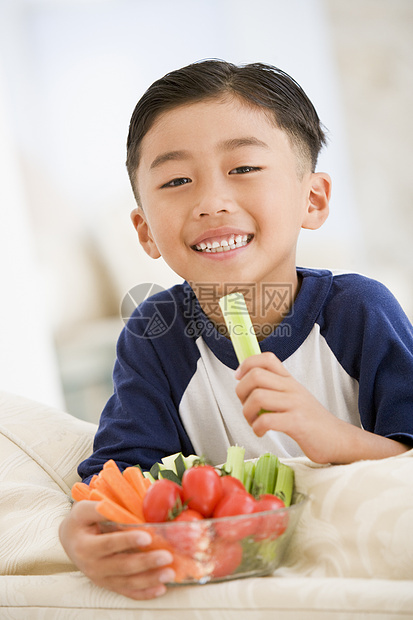 小男孩在客厅里吃一碗蔬菜 笑着图片