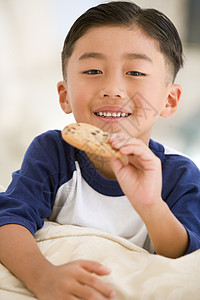 小男孩在客厅吃饼干 笑着头肩享受食物小吃饮食糖果家庭一个男孩甜食儿童图片