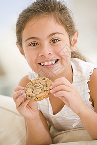 年轻女孩在客厅吃饼干 笑着家庭食物糖果小吃头肩一个女孩巧克力孩子儿童甜食图片