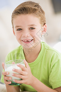在室内喝着微笑的牛奶的年轻男孩小男孩享受儿童奶制品食物孩子们一个男孩玻璃孩子食品图片