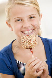 在室内吃着糖苹果微笑的年轻女孩图片