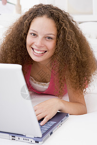 带着笔记本电脑笑着躺在床上的女人技术上网长度微笑互联网家庭客厅休息室女性相机图片