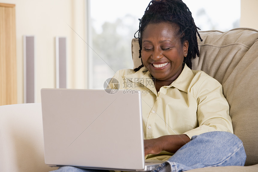 使用笔记本电脑和微笑的客厅妇女水平互联网家庭男人长度上网退休技术沙发女性图片