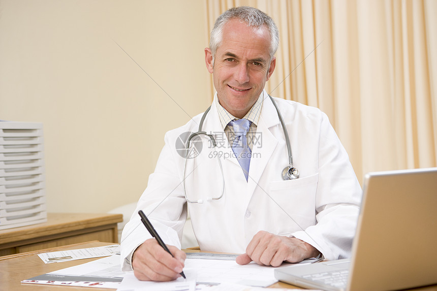 在医生办公室写笔记本电脑的医生桌子男人病历工作服医疗着装大衣工作外科博士图片