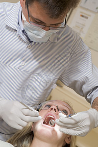 妇女坐在椅子上 在考试室看牙医外科两个人卫生手术男性微笑女性诊所男人牙科图片