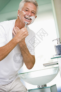 男人在浴室刮胡子和微笑图片