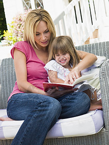 新生儿母亲坐在院子上微笑阅读书的少女和少女背景