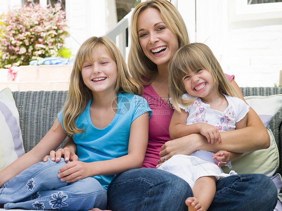 女人和两个年轻女孩坐在院子上微笑图片