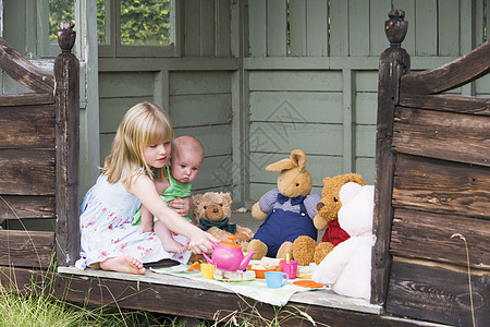 带着婴儿在小屋里玩茶的小女孩图片