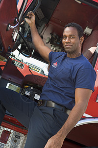 一个消防员站在一辆消防车的出租车旁图片