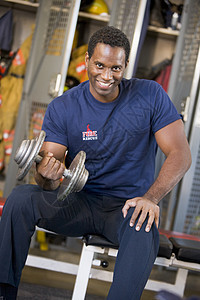 在消防站更衣室对消防员的肖像储物柜锻炼消防队员消防体型举重男人消防服微笑制服图片