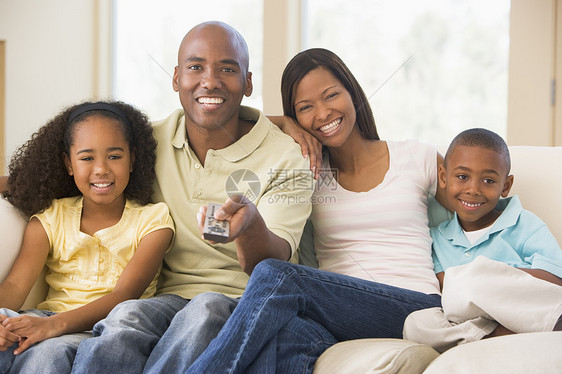 家庭坐在起居室 遥控器笑着微笑父亲男人母亲技术休息室客厅女性频道沙发四个人图片