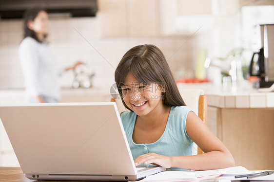 厨房里的年轻女孩 带着笔记本电脑和文件与Wom微笑两个人孩子桌子女性监督妈妈技术拉丁家庭作业母亲图片