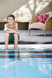 男孩坐在游泳池旁图片