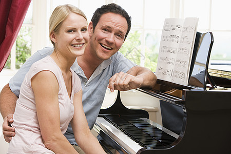坐在钢琴上微笑的一对情侣图片
