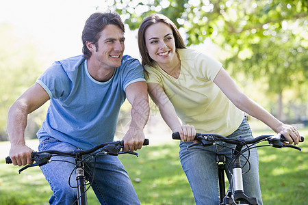 一对在户外骑自行车的夫妇微笑着享受女士男人男性女子丈夫妻子公园骑术两个人图片