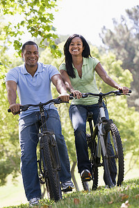 一对在户外骑自行车的夫妇微笑着男人丈夫妻子骑术踪迹农村两个人相机男性享受图片