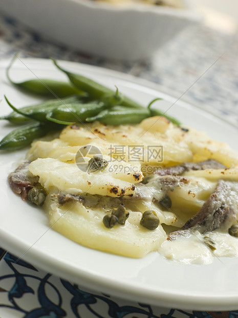 带有绿豆的西班牙式马铃薯土豆豆子香料鳀鱼蔬菜生产美食奶油盘子跳跃图片