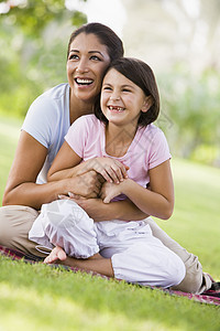 母亲和女儿在户外公园中指着并微笑着家庭情绪妈妈情感女孩女性毯子小学妈妈们幸福图片