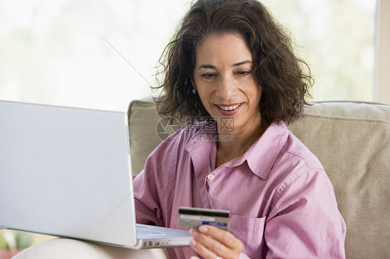 妇女在家里网上购买家庭用品商业信用卡拉丁中年成人电脑零售购物女性笔记本图片