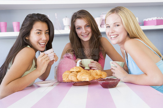 坐在一张桌子上的三个年轻妇女朋友们公司时间黑发食堂食物女性休闲服棕色商业图片