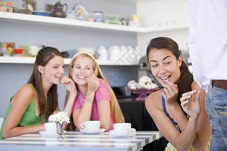 坐在一张桌子上的三个年轻妇女金发咖啡店休闲装着装棕色食物食堂服装朋友们黑发图片