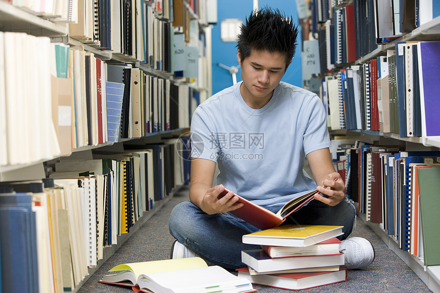 在图书馆阅读书中坐在地板上的人成人校园男性学生教科书青少年书架架子高等教育教育图片