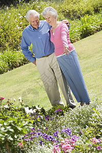 年长夫妇在花园中站立男人女士享受花坛祖父伴侣祖母两个人男性友谊图片
